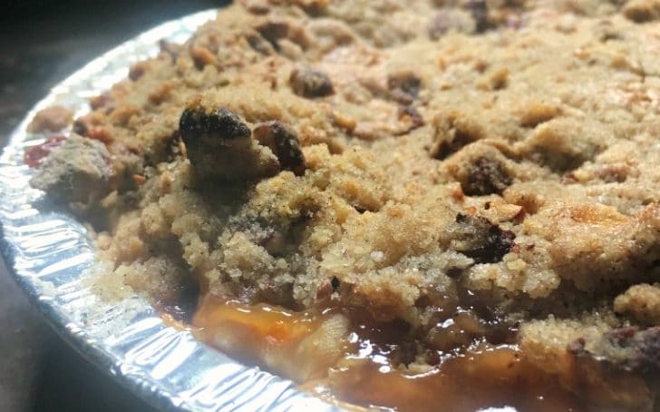A photo of the baked pie - up close from the side Peach Pie with a Pecan Brown Sugar Crumble