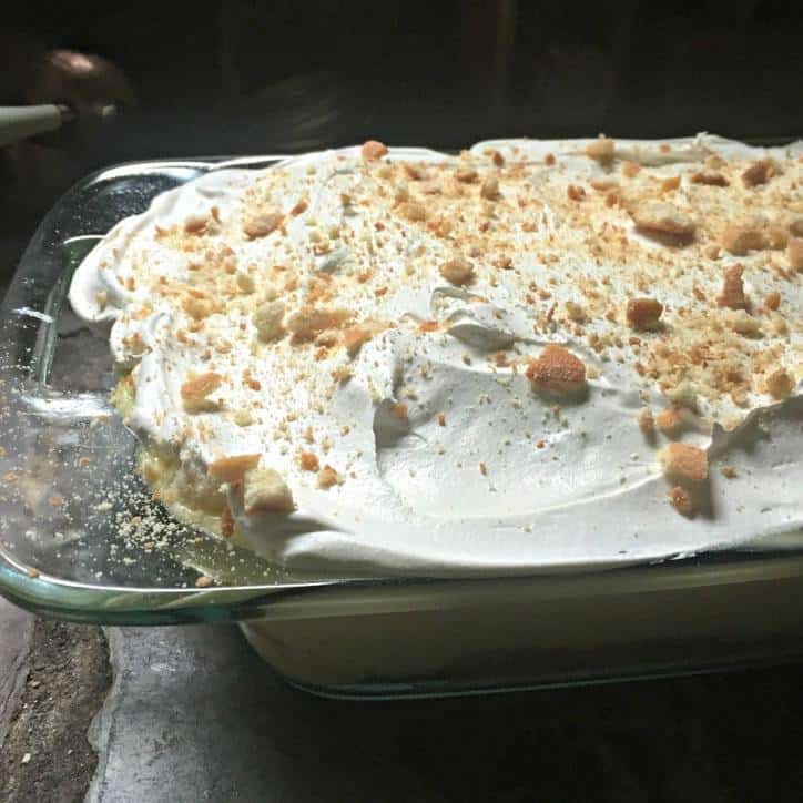 A photo of the finished cake from the side with cool whip topping and crushed vanilla wafers on top