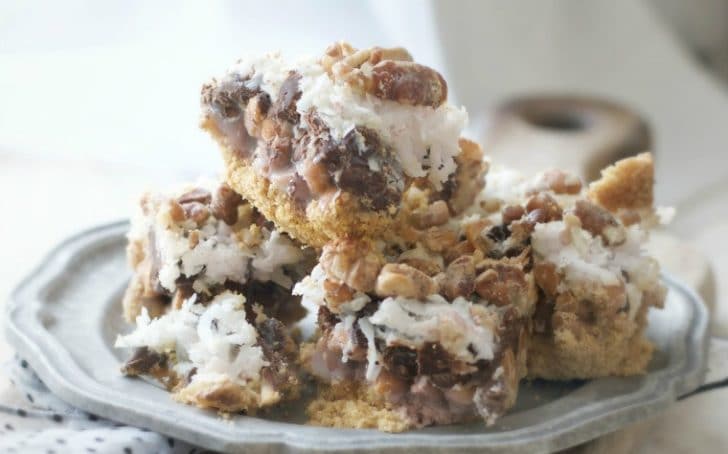 A view from the side of OLD FASHIONED SEVEN LAYER BARS showcasing the gooey drippy sweetened condensed milk layer and the deep rich chocolate