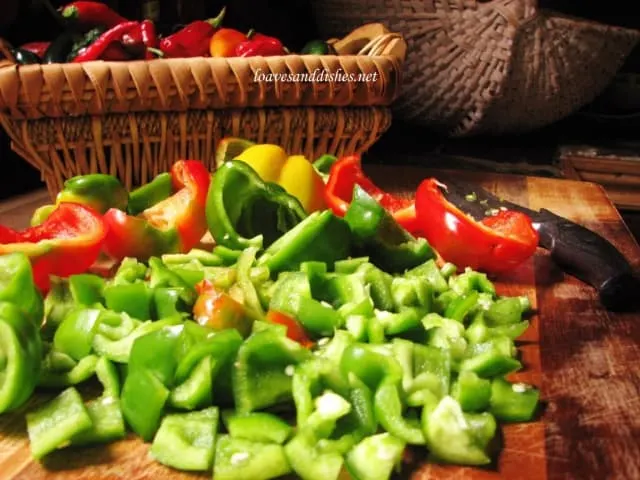 Bell peppers cut into 1 inch pieces with basket in background