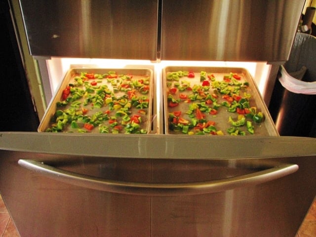 two trays of bell peppers laying on the top of the freezer rack