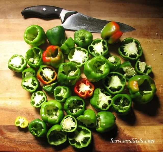 cutting board with peppers cut in half with knife