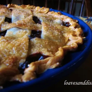 blueberry pie close up in blue pie dish on cutting board