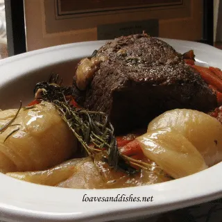 pot roast, onions and carrots in white platter