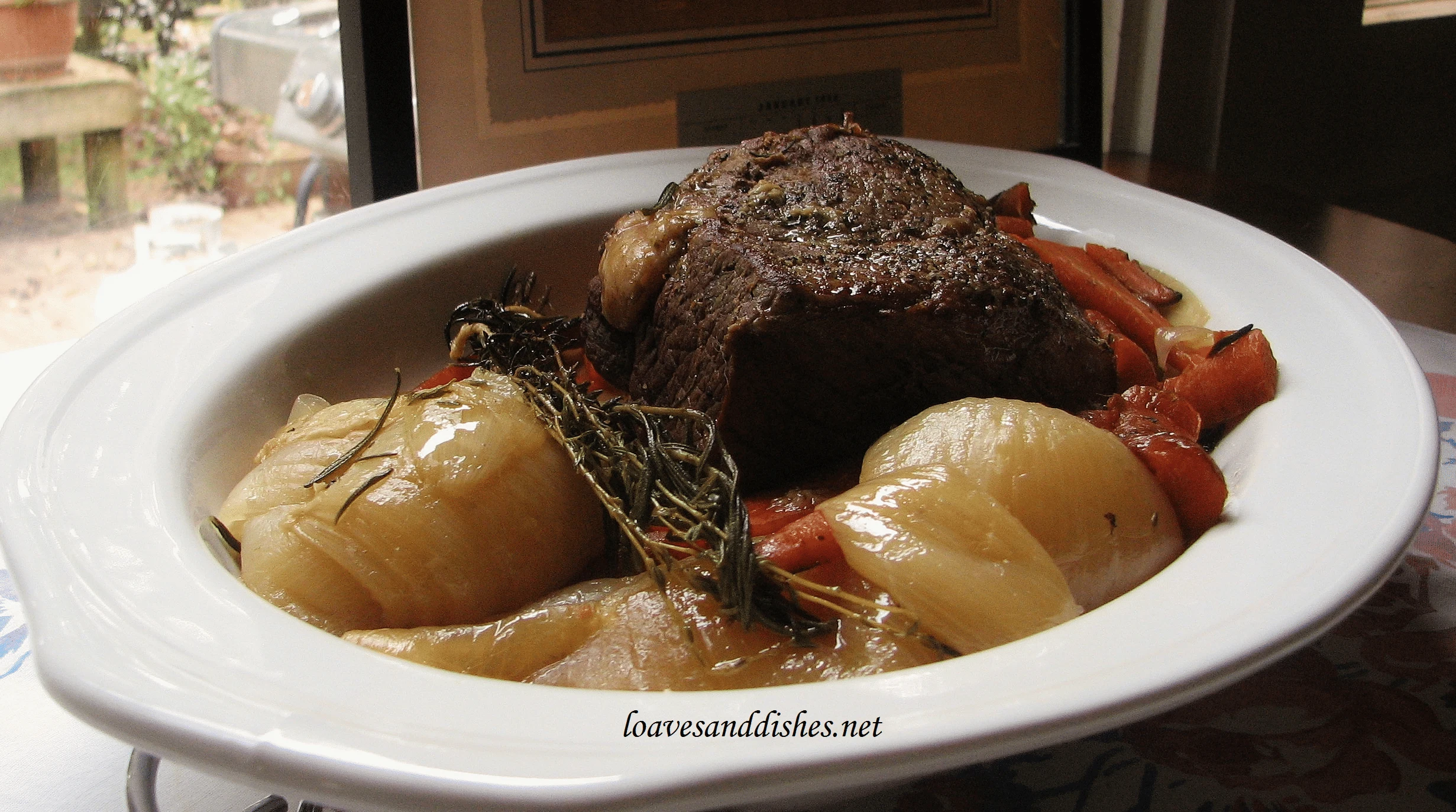 pot roast, onions and carrots in white platter