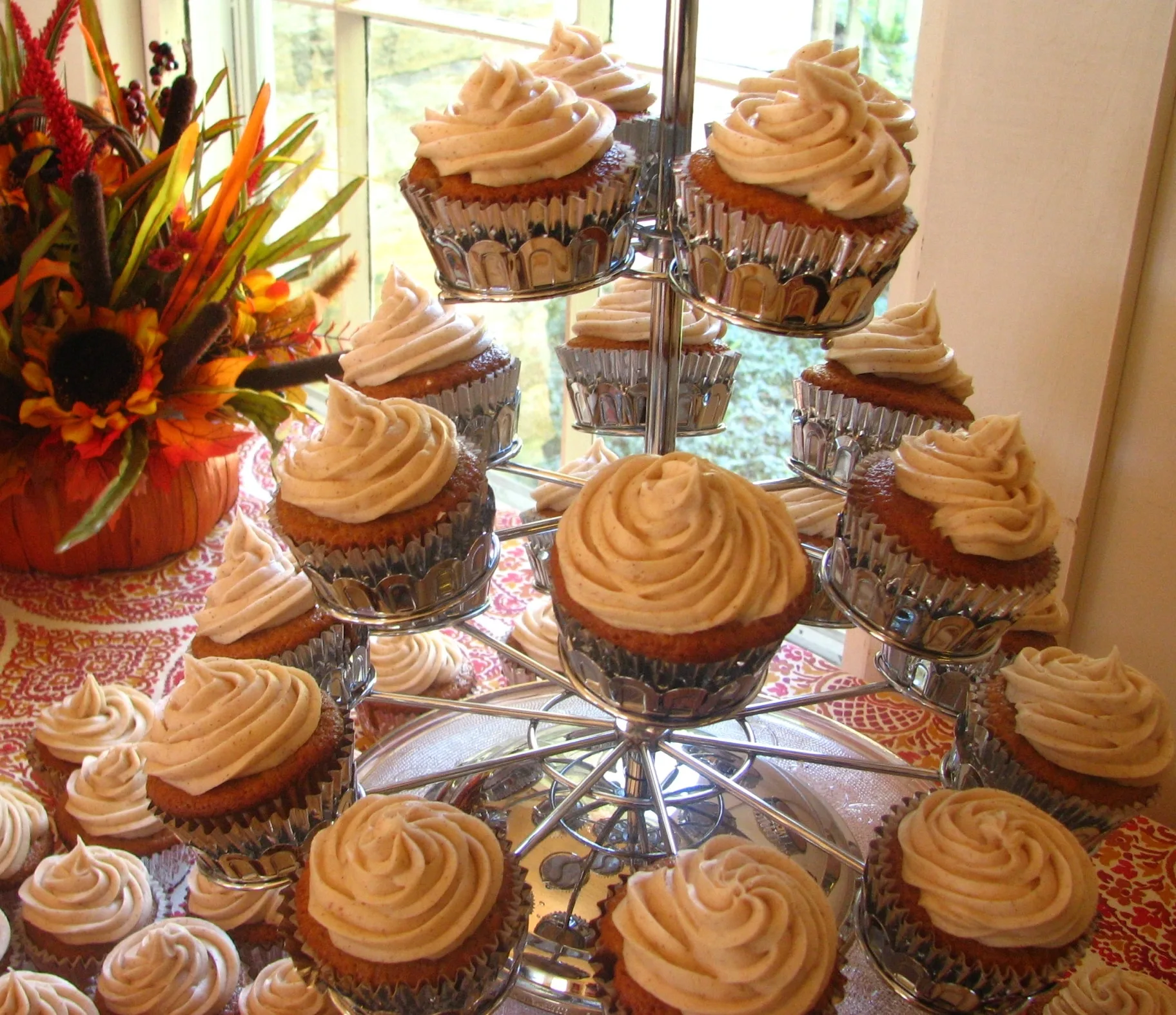 Pumpkin Spice Cupcakes with pumpkin cream cheese icing on cupcake tree with flowers in the back ground