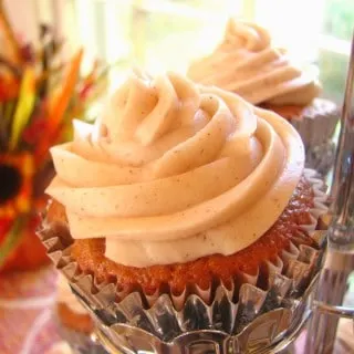 Pumpkin Spice Cupcakes with pumpkin cream cheese icing with flowers in background