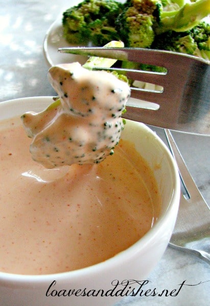 A photo of a bowl of yum yum sauce with broccoli being dipped in