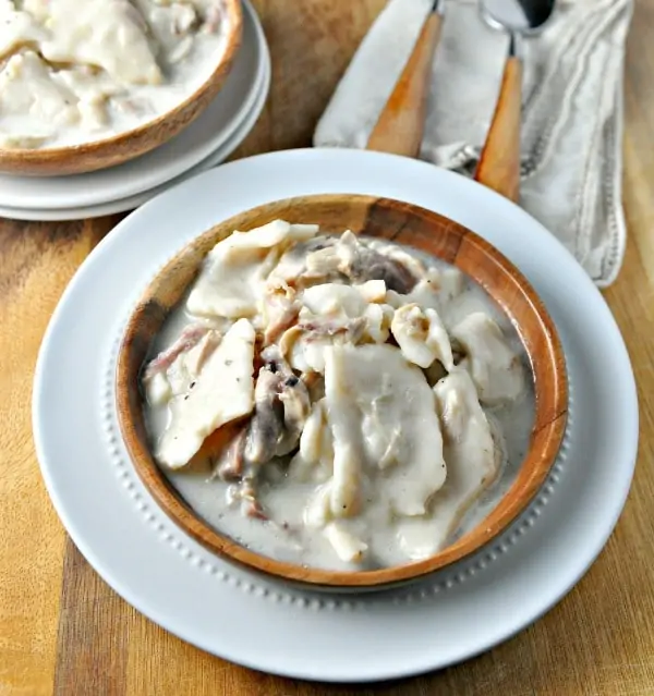 old fashion chicken and dumplins in a wooden bowl on a white plate