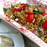 Quinoa salad in a dish with tow spoons and fresh parsley on top