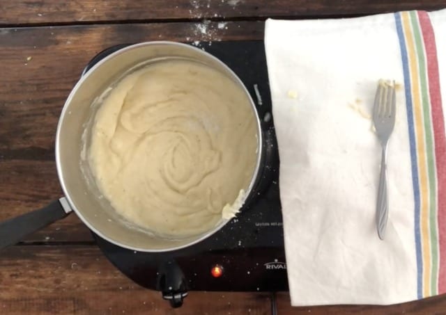 The sauce for cauliflower cheese in a silver pan with towel in background