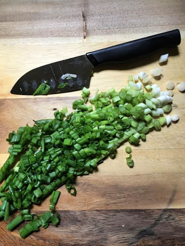 green onions diced on cutting board with knife