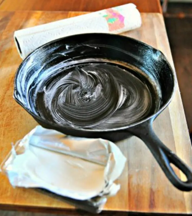 A photo of a skillet with shortening wiped on with a paper towel for how to season a cast iron skillet