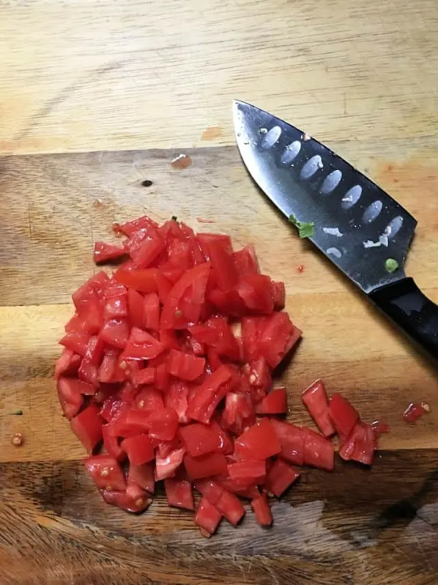 tomato diced with knife on cutting board