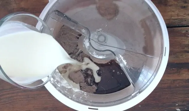 a wet measure adding cream to the mixer bowl