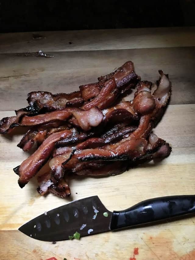 strips of bacon on a cutting board with a knife