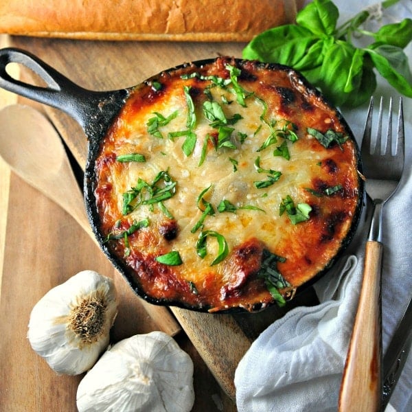 Cheesy Rosemary meatball bake in a skillet sitting on a cutting board with a fork