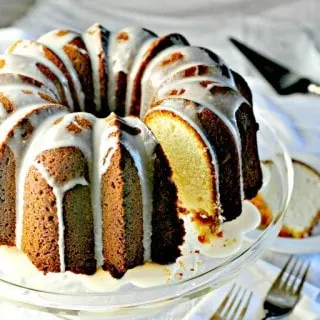 Cream Cheese Pound Cake with icing on top on a glass cake plate