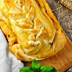 Braided pastry on a cutting board with fresh basil