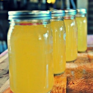 Easy Chicken Stock in jars lined up on a cutting board