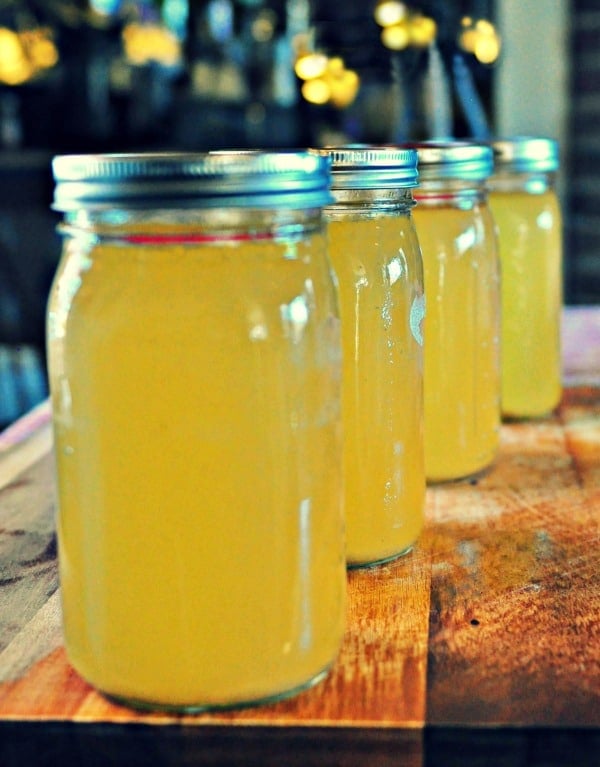 4 jars of canned chicken stock on a wood table