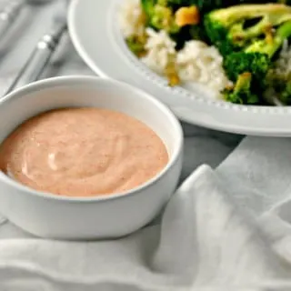 A photo of a bowl of Yum Yum Sauce beside a plate of broccoli and rice for Yum yum sauce