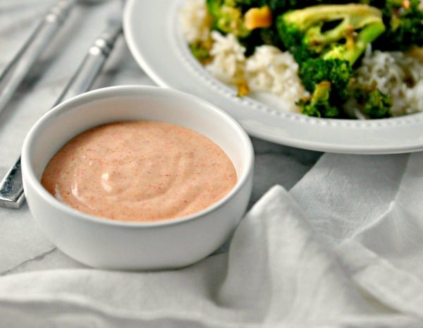 A photo of a bowl of Yum Yum Sauce beside a plate of broccoli and rice for Yum yum sauce