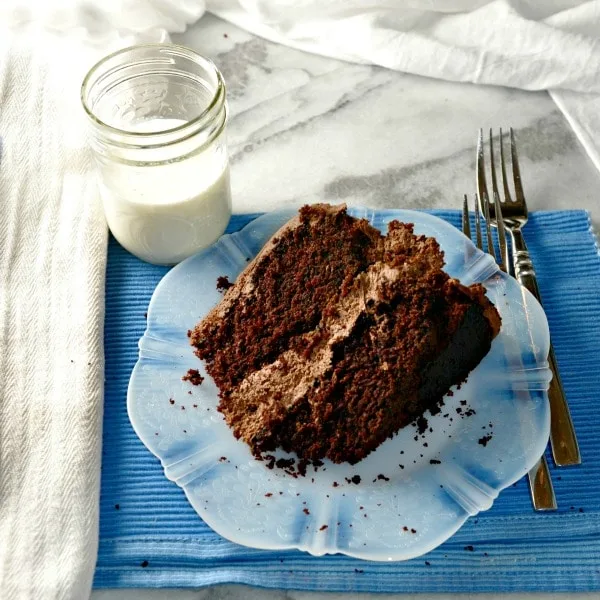 The Chocolate Cake on a plate with two forks and a blue place mat
