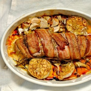 Roasted Rosemary Bacon Wrapped Pork Loin in a white dish on a white table cloth