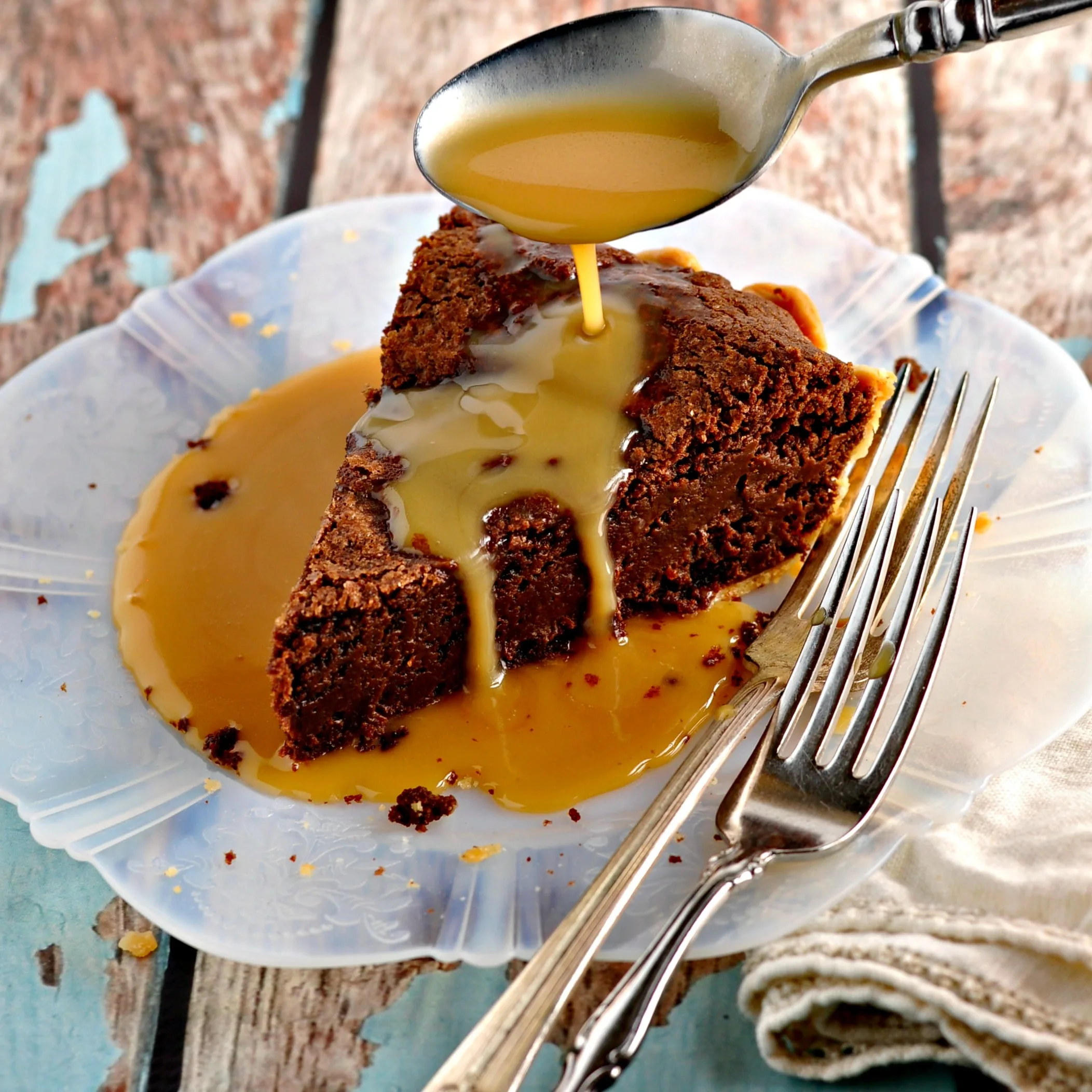 Fudge Pie with Salted Caramel Sauce being drizzled on top with two forks