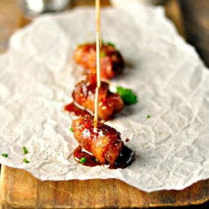 Maple Bacon Wrapped Andouille Bites on parchment paper on a cutting board