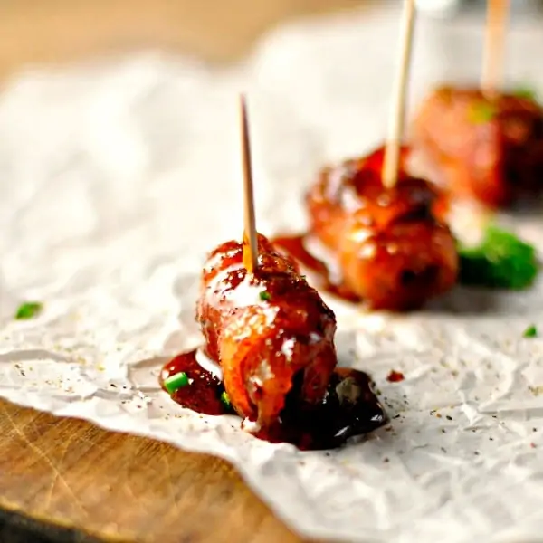 bacon wrapped sausage bites on parchment paper with toothpick