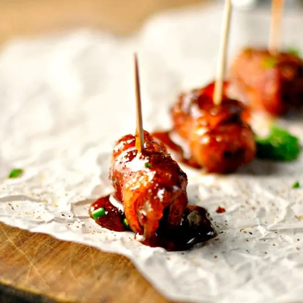 bacon wrapped sausage bites on parchment paper with toothpick