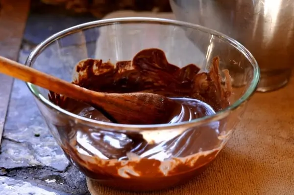 melted chocolate in a clear bowl with a wooden spoon