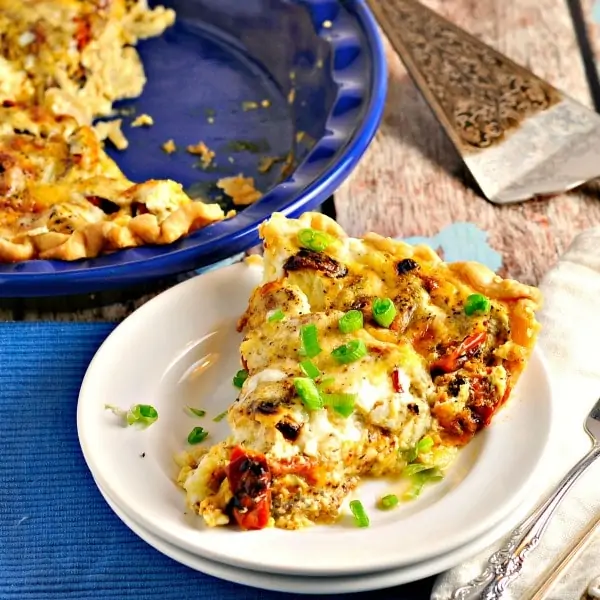 Roasted Tomato and Garlic Quiche in a blue dish with a slice removed and sitting on a white plate