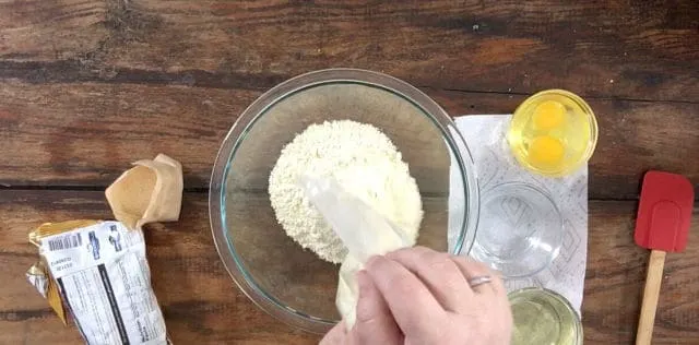 A photo of pouring cake mix into a clear bowl