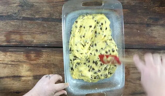 Spreading the cookie mix out into the 9x13 glass baking dish with a spatula