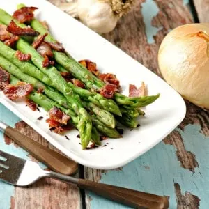 Asparagus on a white plate with bacon sprinkled on top