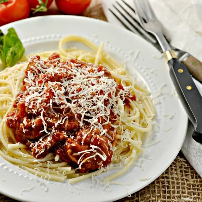 Spaghetti with red mead sauce on a white plate with two forks