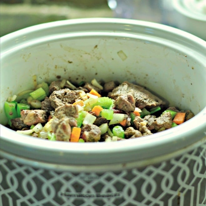 A photo of beef, celery, carrots and the other ingredients all loaded into the crockpot ready to make into classic beef stew