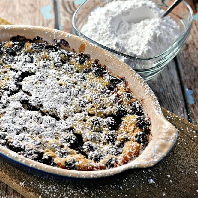 Rustic Blueberry Cake Clafoutis in a baking dish with powdered sugar sprinkled on top