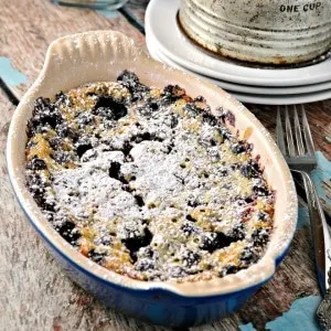 Rustic Blueberry Cake Clafoutis on a wooden table with a fork and powdered sugar