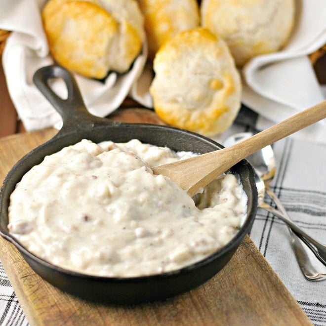 Sausage Gravy in a cast iron skillet with a wooden spoon