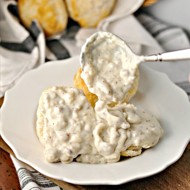 Sausage Gravy on biscuits on a white plate