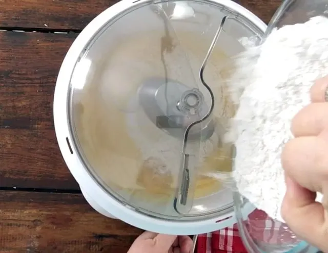 Adding the dry ingredients from a bowl to the wet ingredients in mixer