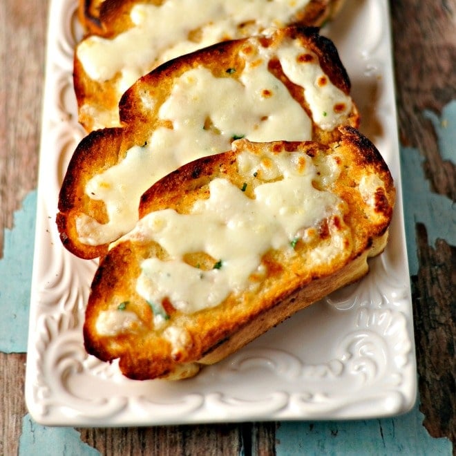 A photo of slices of texas toast with melted cheese on a white plate.