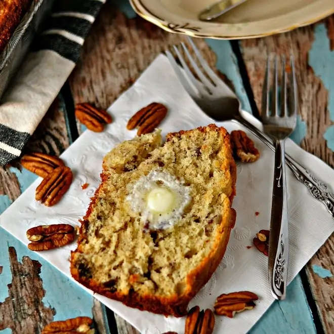 slice of banana bread with pecans, forks and a plate. napkin in background