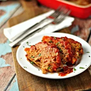 Easy Tasty Meatloaf slices on a white plate with red sauce on top