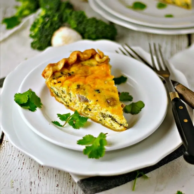 A slice of Vegetable Cheddar Quiche on a white plate with two forks