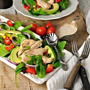 southwest chipotle chicken salad on a white plate with two forks and cherry tomatoes sprinkled around the plate